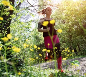 Joggerin läuft im Frühling auf einem Waldweg