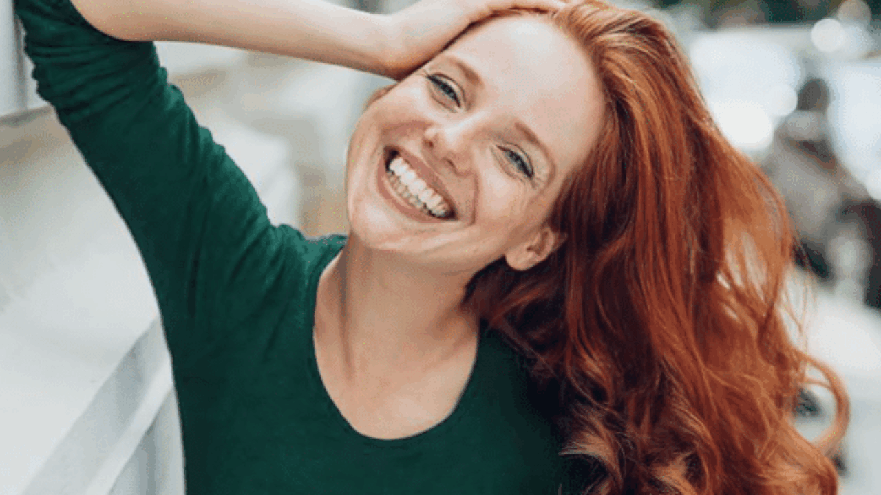Frau mit leuchtend roten Haaren auf einem Spaziergang durch die Stadt