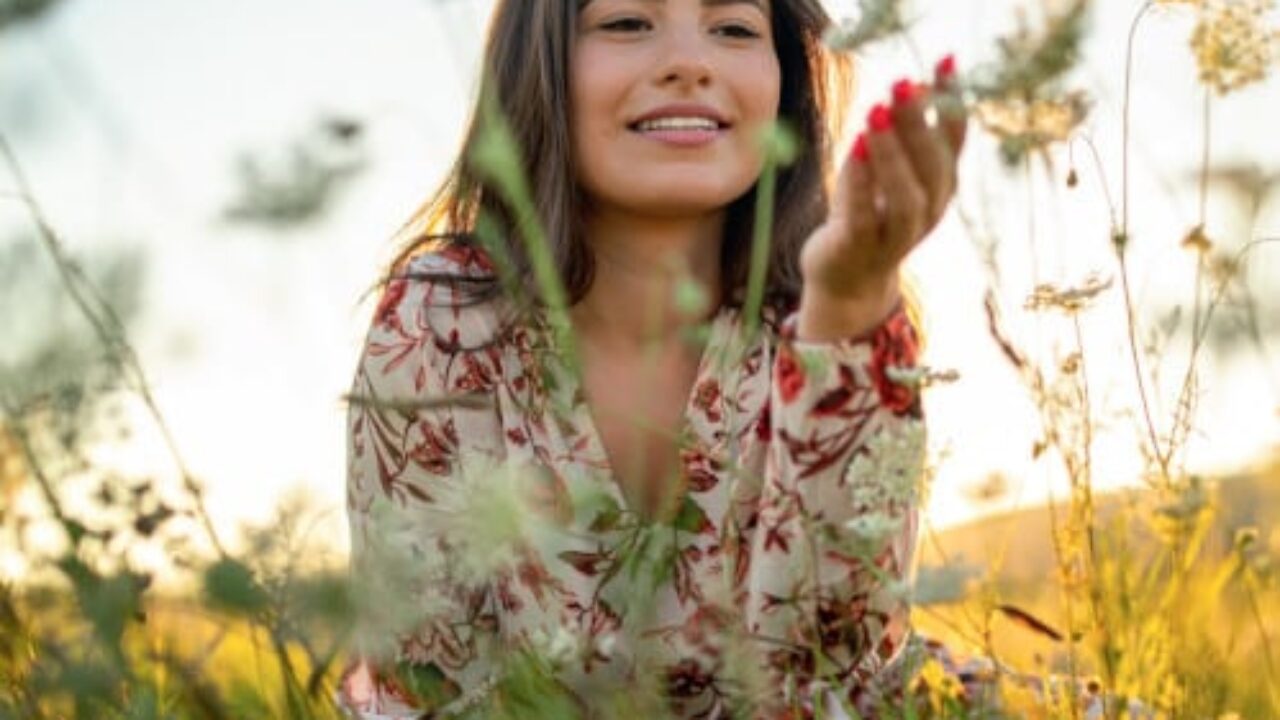 Junge frau mit farbenfroher Sommerkleidung auf einer Blumenwiese