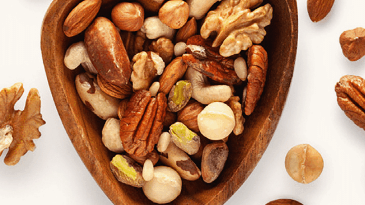 verschiedene Arten von Nüssen in einer herzförmigen Holzschale